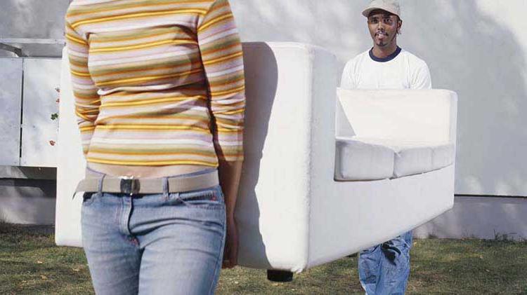 A couple carry their wife sofa into their new place.